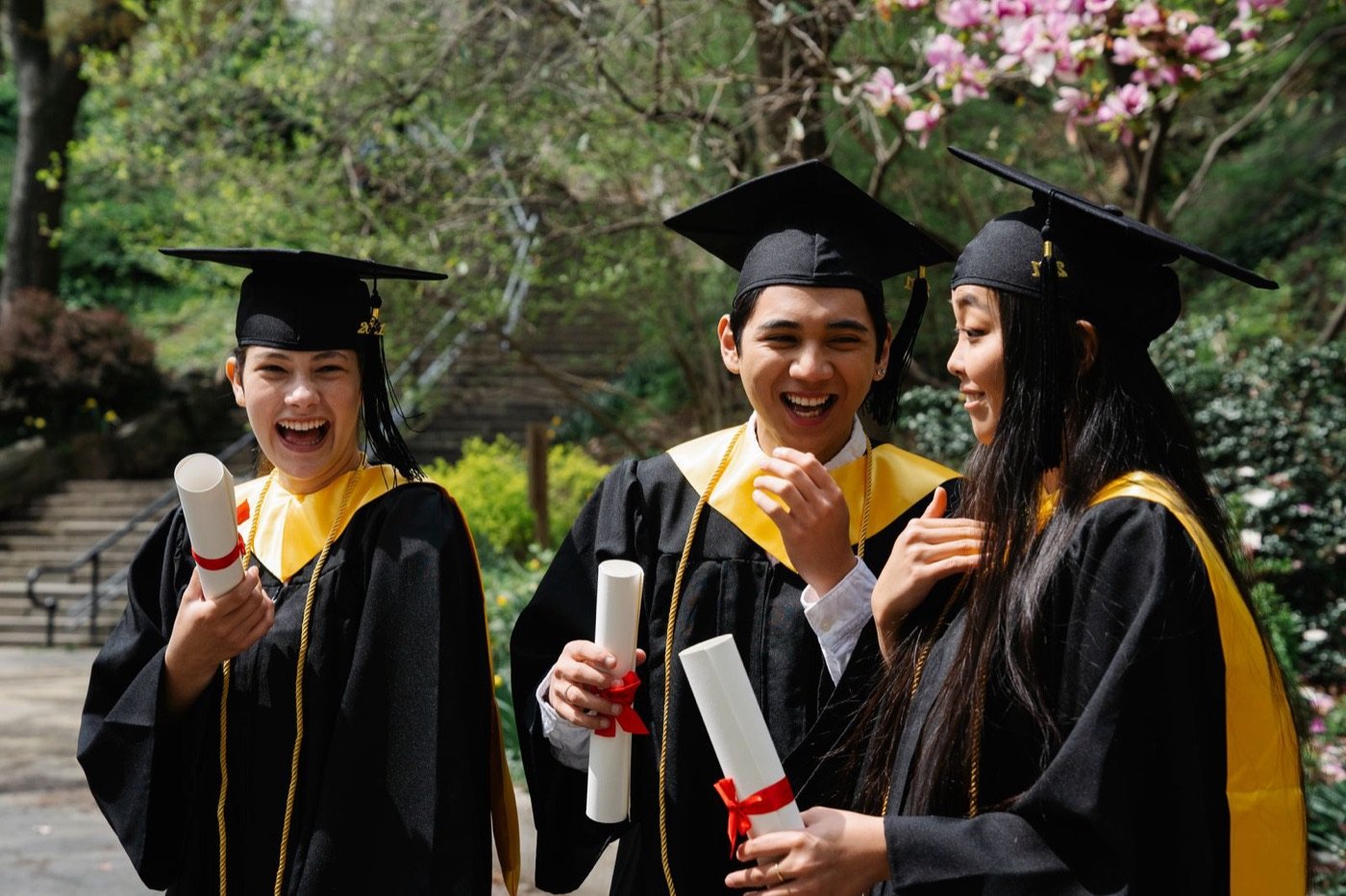 Graduates celebrating together outdoors with their diplomas